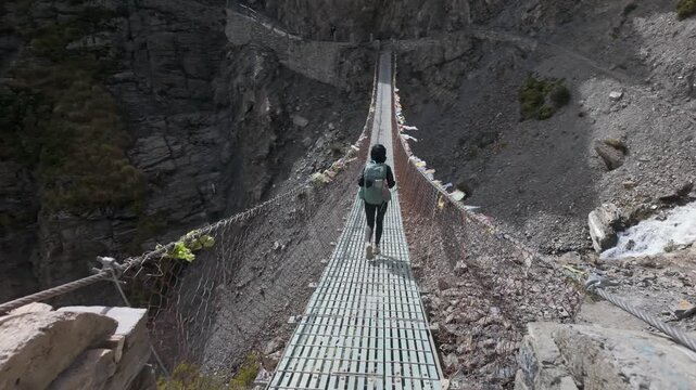 High Altitude Trekking Solo Traveler on Prayer Flag Bridge at Annapurna circuit trek on the way to Tilicho lake.