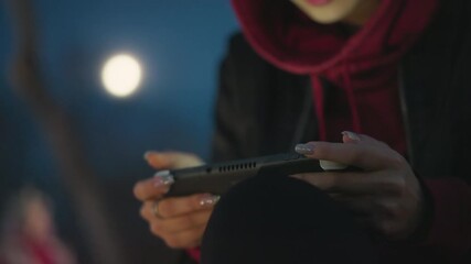 Night Gaming Focus, Focused Woman Engages In Handheld Gaming Session, Evening Scene With Woman Concentrating On Mobile Game, Asian Female Player With Intense Focus On Her Handheld Device At Night