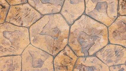 A wet, orange-brown stamped concrete footpath with an irregular stone pattern. An abstract background or backdrop for design projects or urban street environments.
