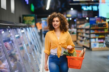 Woman carrying shopping basket in supermarket aisle