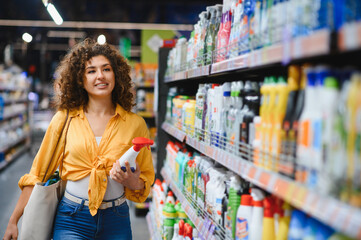 Woman buying cleaning products at supermarket aisle