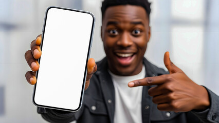 Enthusiastic young man pointing at a modern mobile device with a clean white screen, ready for your creative advertisement or digital content display