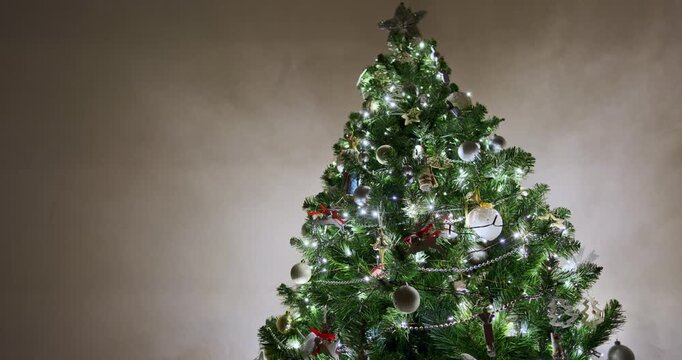 Decorated Christmas tree with silver baubles, wooden reindeer ornaments with red ribbons, ballerina and mouse toys, glowing fairy lights and bead garlands. Christmas tree decorations