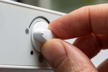 Close up of male hand setting freezer temperature control knob for safe food storage and efficient daily energy use at home