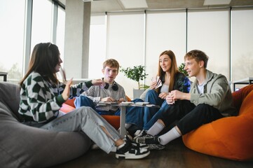 Obraz premium Group of teenagers playing cards on beanbag chairs