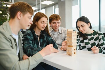 Students playing jenga, having fun together in modern office