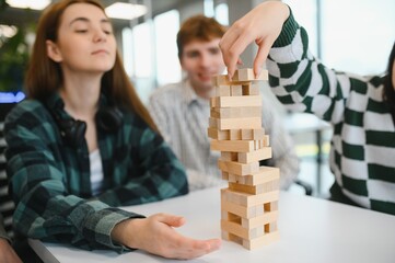 Friends playing stacking block game in office break room