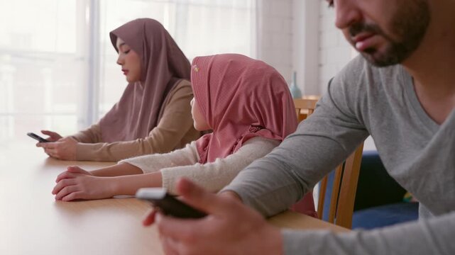 Muslim parents addicted to their phones, ignoring their young daughter. 