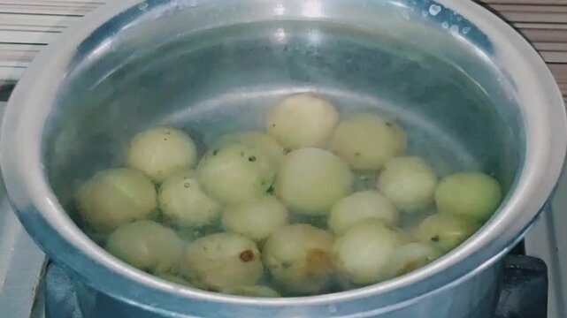 boiling fresh indian gooseberries in pot during essential cooking stage