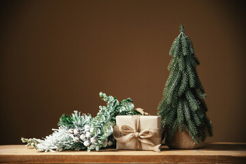 Gift box, fir tree and Christmas ornaments over brown background with copy space. Festive winter holiday backdrop. Design for banner or greeting card