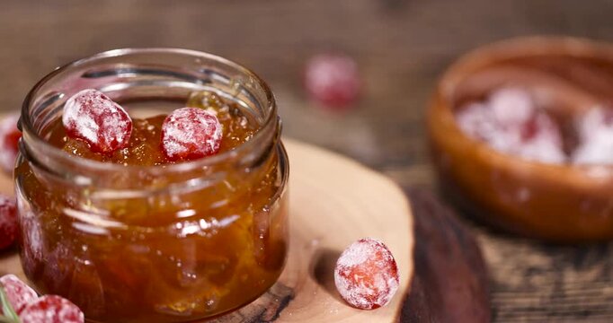 orange jam made from oranges and citrus fruits and dried in sugar syrup, kumquat fruits in white powder, a glass jar with sweet orange jam is on the table