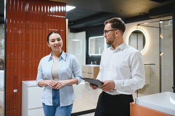 Woman choosing bathroom tiles with sales assistant