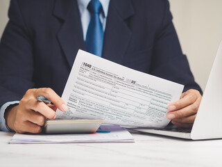 Businessman reviewing tax document with calculator.