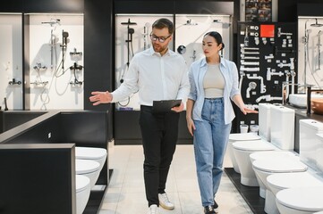 Obraz premium Shop assistant showing toilets to customer in bathroom furniture store