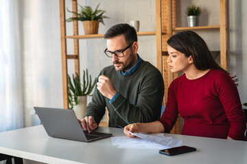 Pregnant wife with husband making online payment using credit card on laptop at home