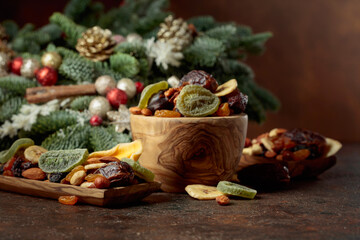 Dried fruits and nuts with Christmas wreath on a brown vintage table.
