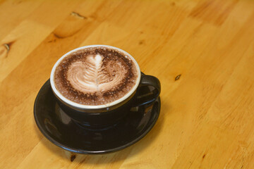 Hot chocolate in a black cup on a wooden table.