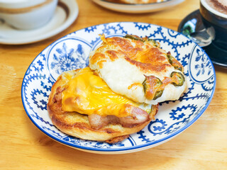 Close up, A bagel with pickled jalapeno, cheese, and egg on a wooden table. Breakfast concept.