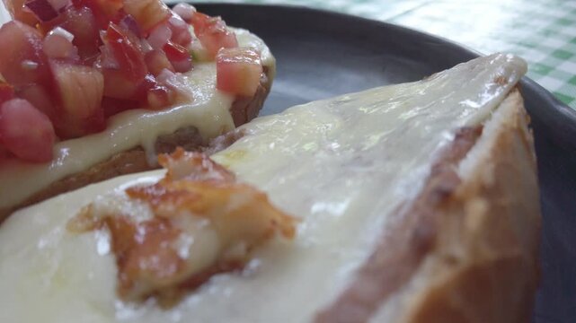 Close-up of authentic Mexican molletes featuring bolillo bread, refried beans, melted cheese, and fresh pico de gallo salsa.