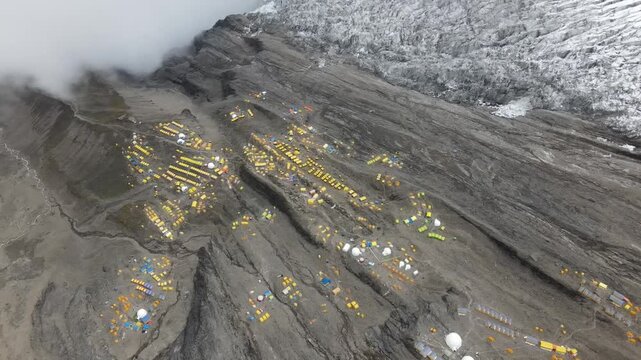 Drone footage showcases Manaslu Base Camp below the 8,163m Himalayan peak. The scene reveals snowy ridges, rugged terrain, and the dramatic high-altitude environment of this remote mountain region.