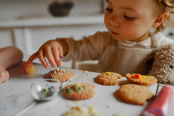 Happy children decorating Christmas cookies at home.