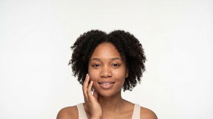 Headshot portrait of a happy young African American woman with natural curly afro hair touching her clean, healthy skin.