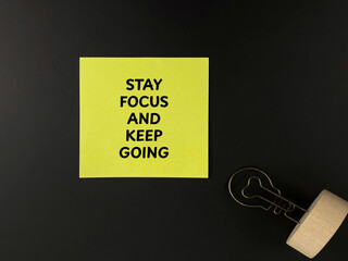 Motivational quote concept. Stay Focus And Keep Going written on yellow sticky note over dark background.