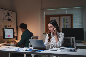 Asian businesswoman working late night and talking on phone