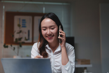 Woman talking on phone and working using laptop