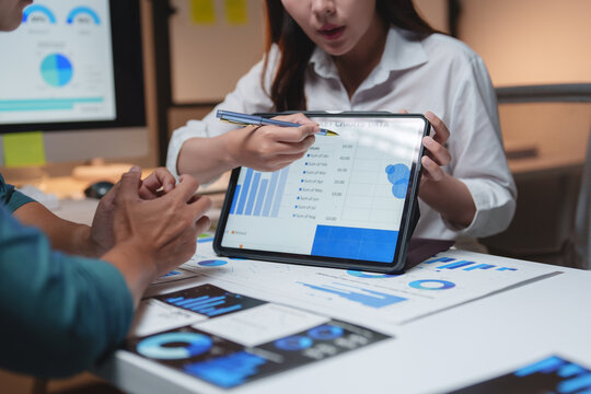 Business colleagues analyzing marketing data on tablet during meeting