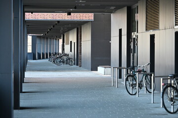 River embankment passage under a modern building colonnade with bicycle parking
