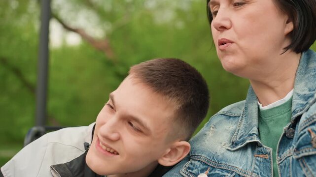 Woman Gently Embraces Son Outdoors, Mother Offers Calming Support To Disabled Child In Park Environment, Caring Mother Softly Holds And Comforts Her Physically Challenged Son Outdoors In Park