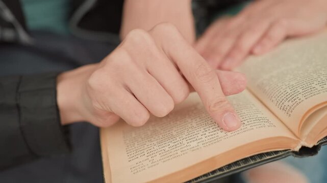 Finger Following Lines In Open Book CloseUp Showing Guided Reading Index Fingertip Traces Text Across Worn Pages, Steady Hand And Attentive Posture Highlight Decoding And Comprehension, Intimate