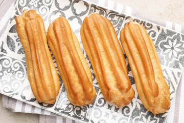 Fresh tasty eclairs on light table, top view