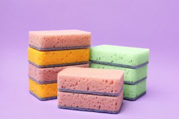 Different kitchen sponges on violet background, closeup