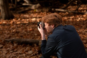 Man captures nature's beauty with camera in tranquil autumn forest
