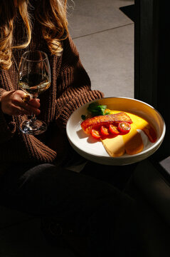 A girl holds a salmon steak with a glass of wine