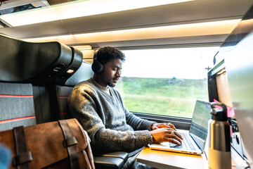 Young man working on laptop traveling by train © unai