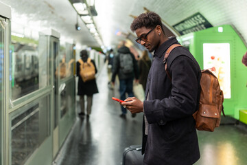 Young black man checking smartphone in subway station