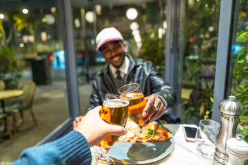 Friends toasting beer glasses enjoying dinner at restaurant