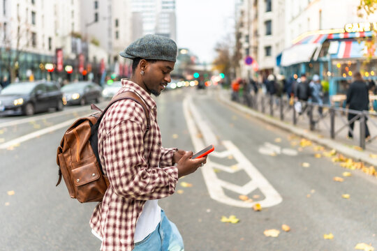 Young man crossing city street checking phone - Powered by Adobe