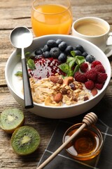 Healthy breakfast. Oatmeal with nuts, berries and yoghurt in bowl on wooden table, closeup
