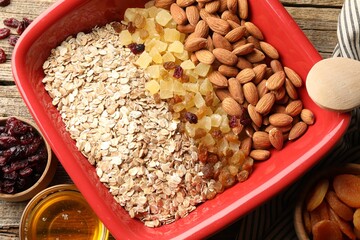 Making granola. Oat flakes, dried fruits, almond nuts and honey on wooden table, flat lay