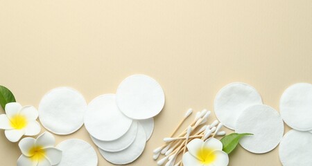 Clean cotton pads, swabs and flowers on beige background, flat lay. Space for text