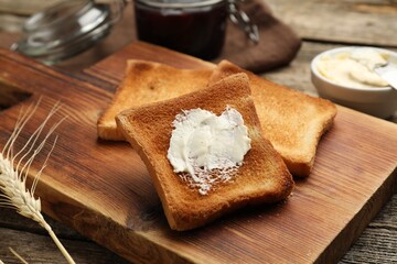 Slices of toasted bread with butter on wooden table, closeup
