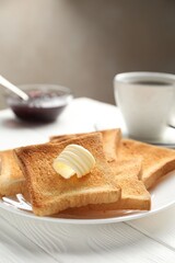 Fresh toasted bread slices served with butter and tea on white wooden table, closeup. Space for text