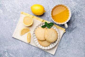 Tasty lemon cookies and fruit slices on grey table, flat lay