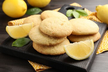 Tasty lemon cookies and fruit slices on dark wooden table, closeup