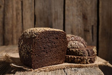 Delicious fresh rye bread with sesame seeds on wooden table, closeup