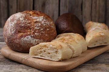 Different types of bread on wooden table, closeup